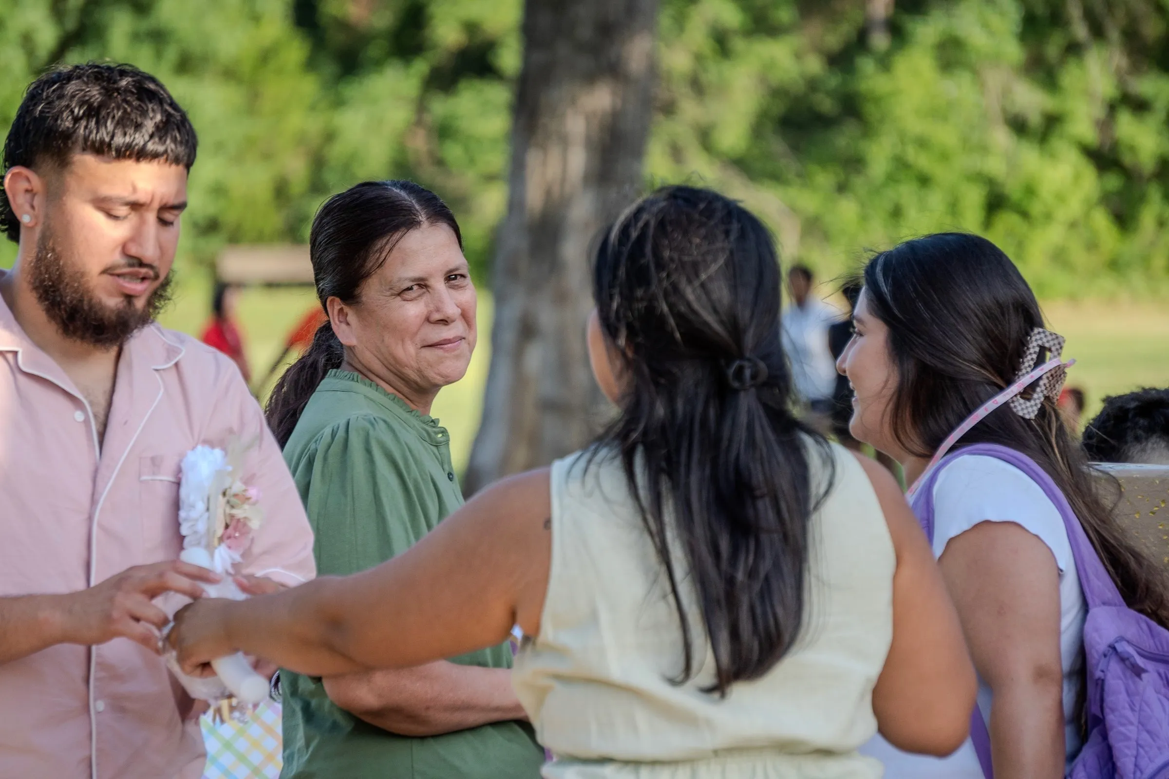 Guests greet each other under the trees at an outdoor celebration