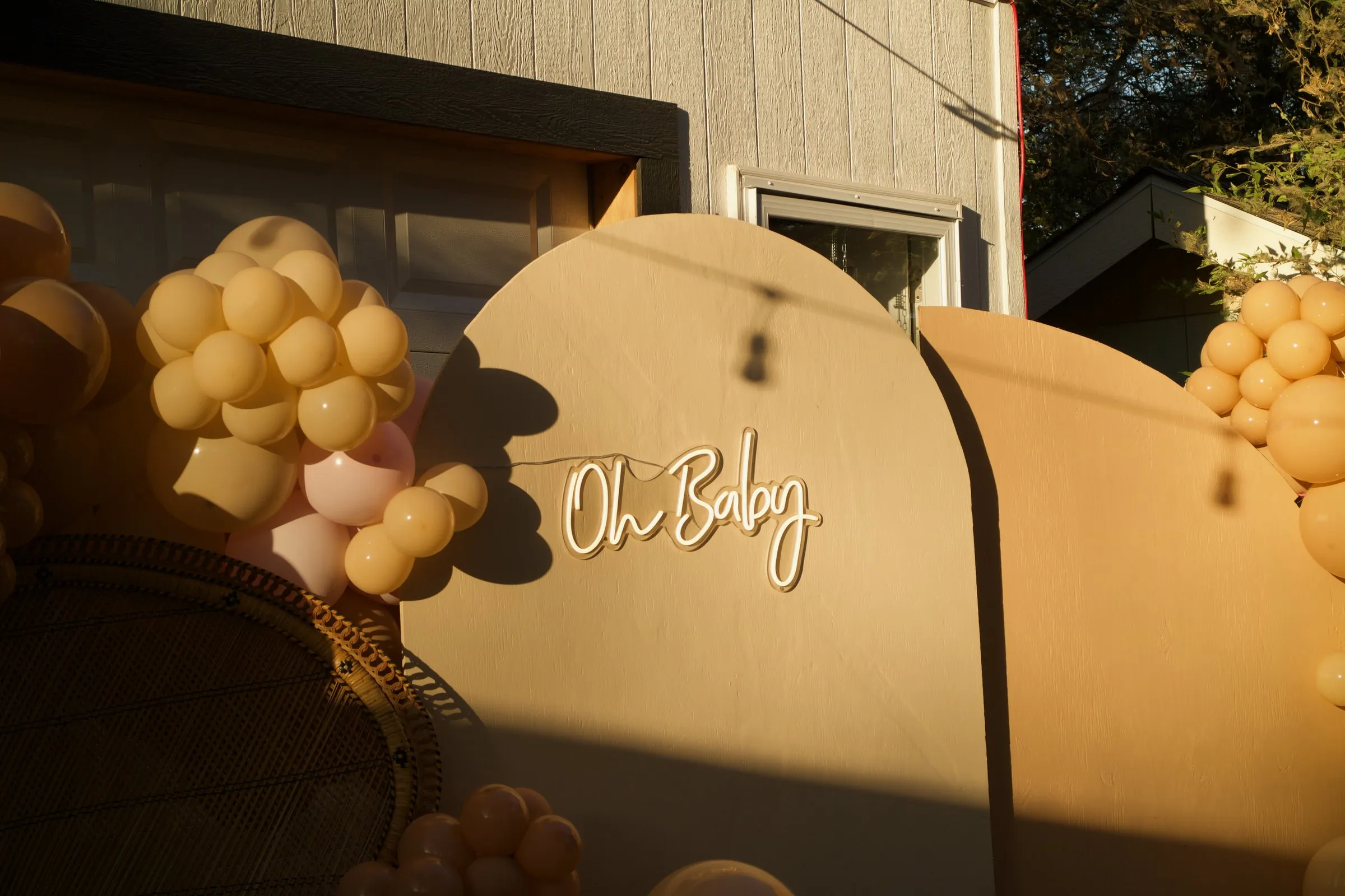 Evening light and shadow across an Oh Baby sign and balloons