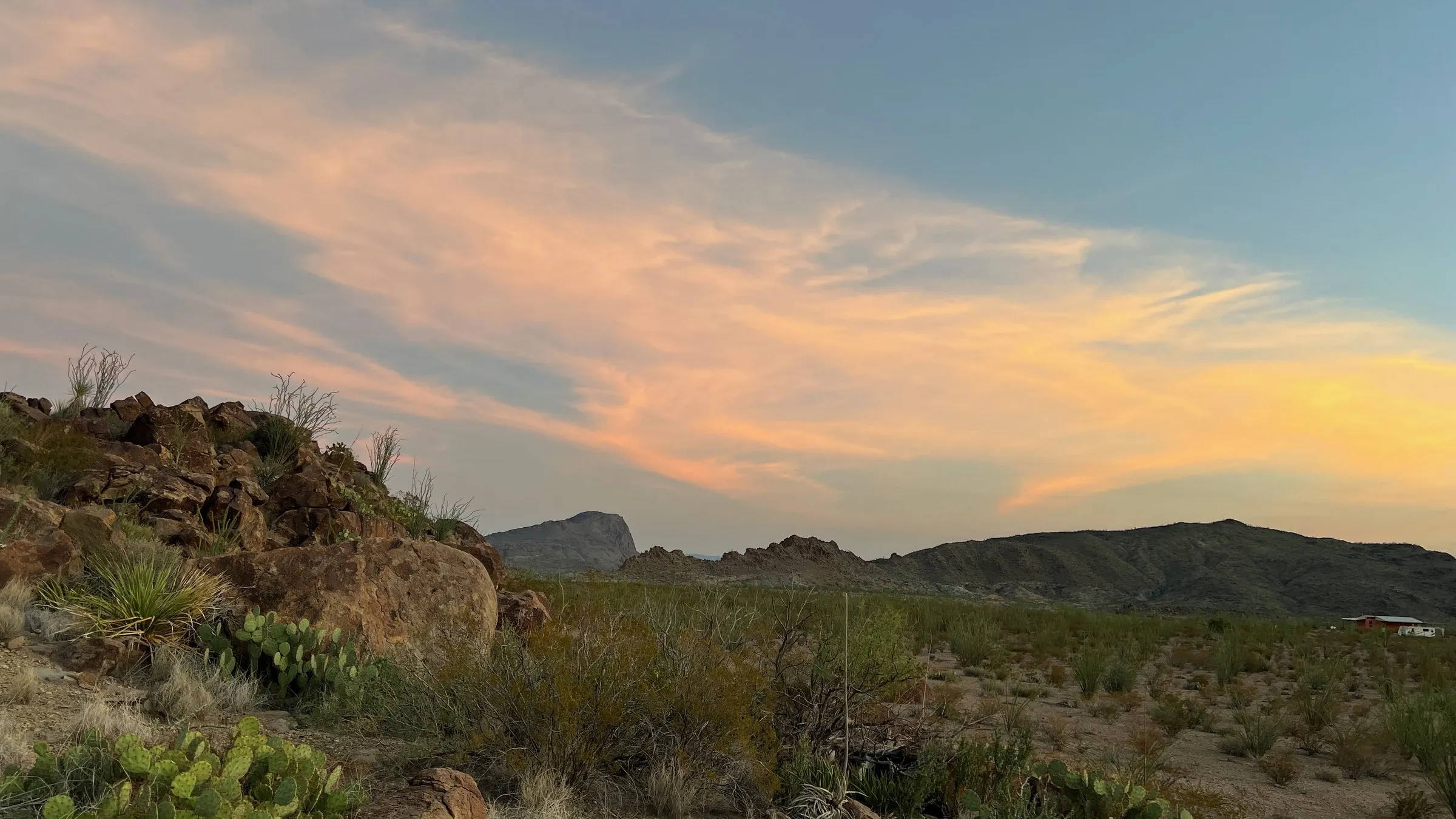 Pink and orange clouds over a West Texas desert ridge at sunset